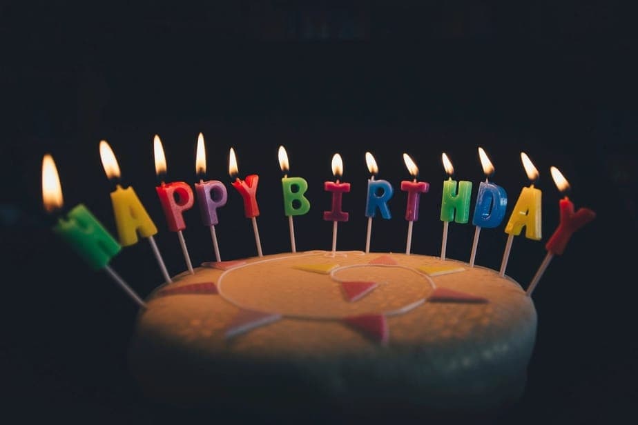 촛불이 켜진 생일 케이크가 놓인 어두운 테이블